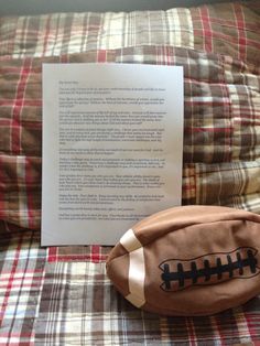 a stuffed football sitting on top of a bed next to a piece of paper