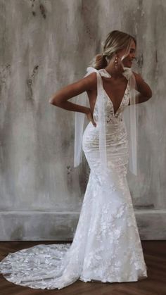 a woman in a white wedding dress standing on a wooden floor with her back to the camera