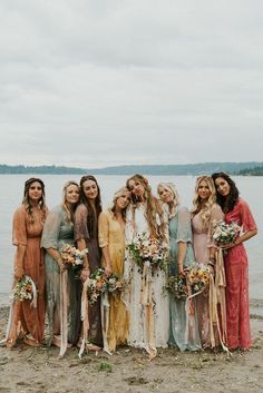 a group of women standing next to each other on a beach with flowers in their hair