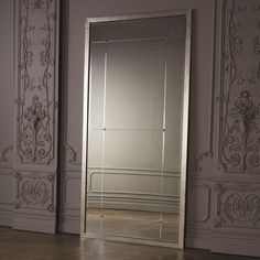 a large mirror sitting on top of a floor in front of a wall mounted cabinet