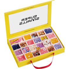 a yellow box filled with lots of different types of candies on top of a white surface