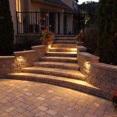 some steps lit up with lights in front of a house and flowers on the side