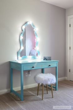 a blue vanity table with a mirror and lights on it