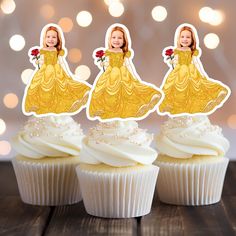 three cupcakes with white frosting and yellow dresses on them are sitting next to each other