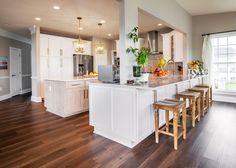 a large kitchen with white cabinets and wooden flooring, along with an island in the middle