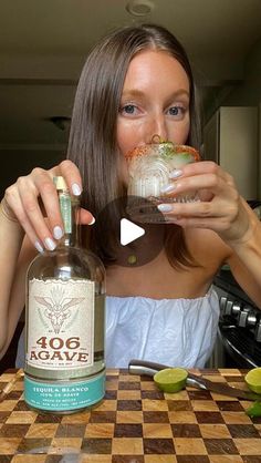 a woman sitting at a table with a bottle of alcohol in front of her face