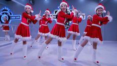 a group of people dressed in santa outfits dancing on a dance floor with their hands up