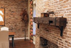 a brick fireplace in a living room next to a chair and table with a painting on the wall