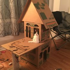 a cat sitting on top of a cardboard house made to look like it's been built