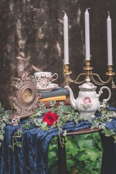 a table topped with books and candles on top of a blue cloth covered tablecloth