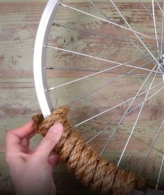 a hand holding a rope next to a bicycle wheel