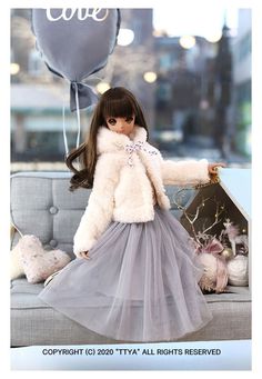 the doll is wearing a gray dress and fur coat