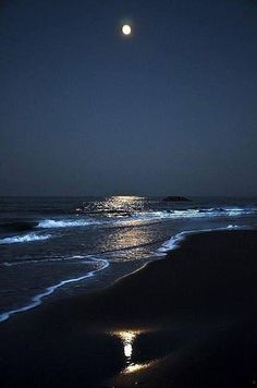 the moon is shining over the ocean at night