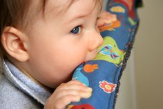 a close up of a baby chewing on a pillow