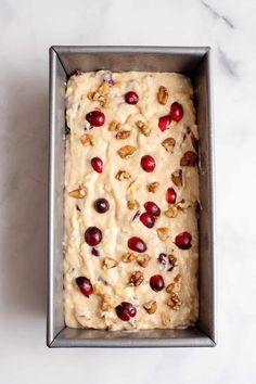 a loaf of bread with cranberries and walnuts on top in a pan