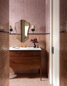 a bathroom with pink tile and wooden vanity in the corner, along with a large mirror