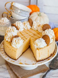 a pumpkin cheesecake on a plate with two slices taken out and the rest of the pie in the background