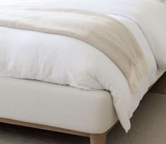 a bed with white sheets and pillows in a room