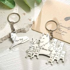 three keychains with dogs on them sitting next to a card and some leaves