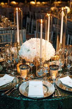 the centerpieces on this table are filled with flowers, candles and silverware