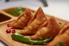 some food is on a wooden plate with green peppers and sauce in the bowl next to it