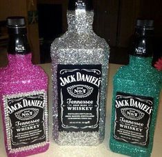 three bottles of jack daniels are sitting on a counter top, one is green and the other is pink