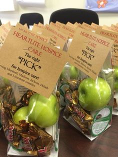 four bags filled with green apples sitting on top of a wooden table next to each other