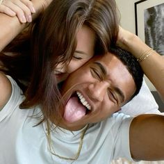 a man and woman laughing while holding their heads together