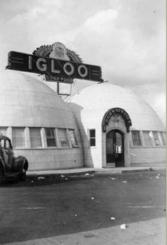 an old truck parked in front of a building with a large sign on it's roof