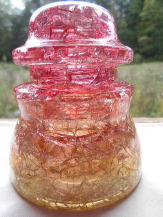 a close up of a glass vase with red and yellow designs on the top, sitting on a table