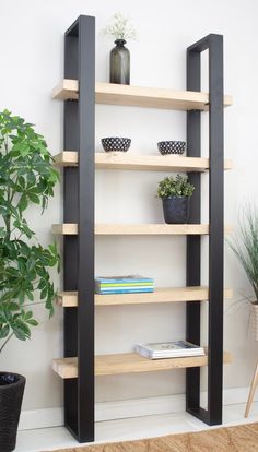 a book shelf with books and plants on it in front of a wall mounted planter