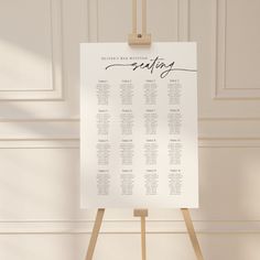 a seating chart on a wooden easel in front of a white wall