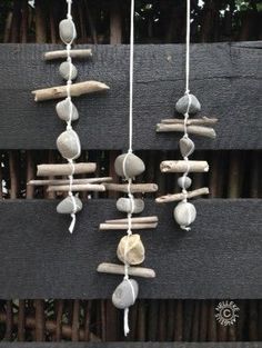 a wind chime made out of rocks and driftwood is hanging on a fence