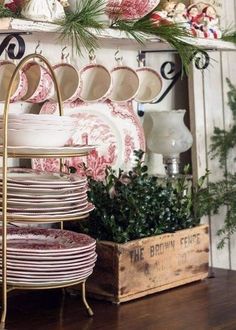 a stack of plates sitting on top of a wooden table next to a shelf filled with dishes