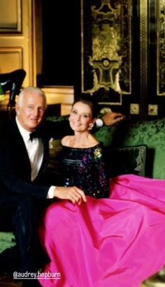 an older man and young woman sitting on a green couch in formal wear, posing for the camera