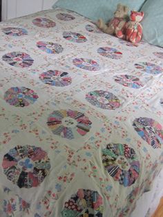 a bed with a quilted bedspread and teddy bears on it