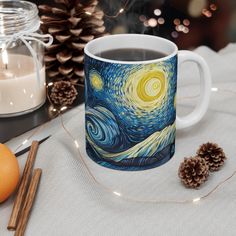 a coffee mug sitting on top of a table next to some pine cones and candles