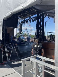 the crowd is waiting for their turn to perform at an outdoor concert venue with a ferris wheel in the background