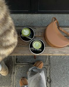 a cat sitting on the ground next to two bowls with food in them and a woman's feet