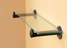 a glass shelf mounted to the side of a wall with two wheels on each end