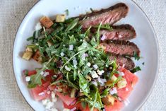 a white plate topped with steak and watermelon salad