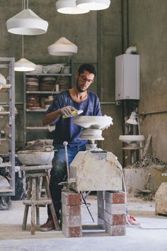 a man sitting on top of a white bowl in a room filled with lots of lights