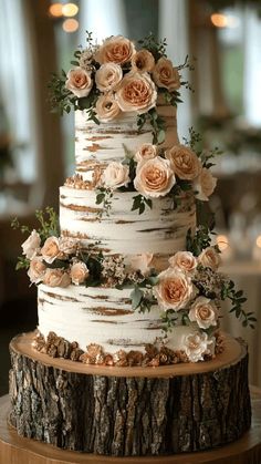 a three tiered cake with flowers on the top is sitting on a tree stump