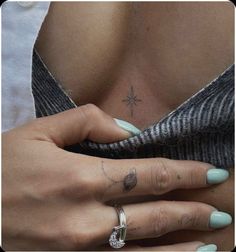 a woman's hand with a cross tattoo on her left arm and the other hand