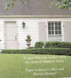 a house with white shutters and two potted plants on the front lawn in front of it