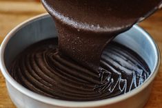 a spoon is pouring chocolate into a bowl