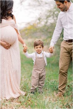 a little boy holding the hand of his mom and dad