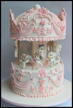 a carousel cake with pink icing and white frosting on the top is shown