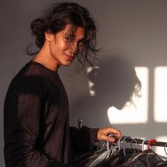 a man standing next to a bike in front of a wall with shadows on it