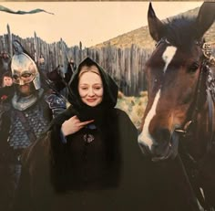 a woman standing in front of a painting with horses and knights on the wall behind her